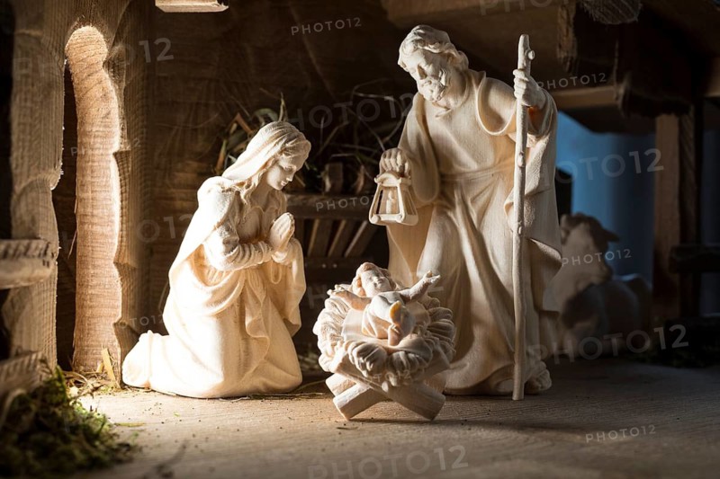 The Holy Family at the crib, wooden crib figurines represent the birth of Jesus Christ Child lying in a crib in a stable as a little Christ Child, Christmas