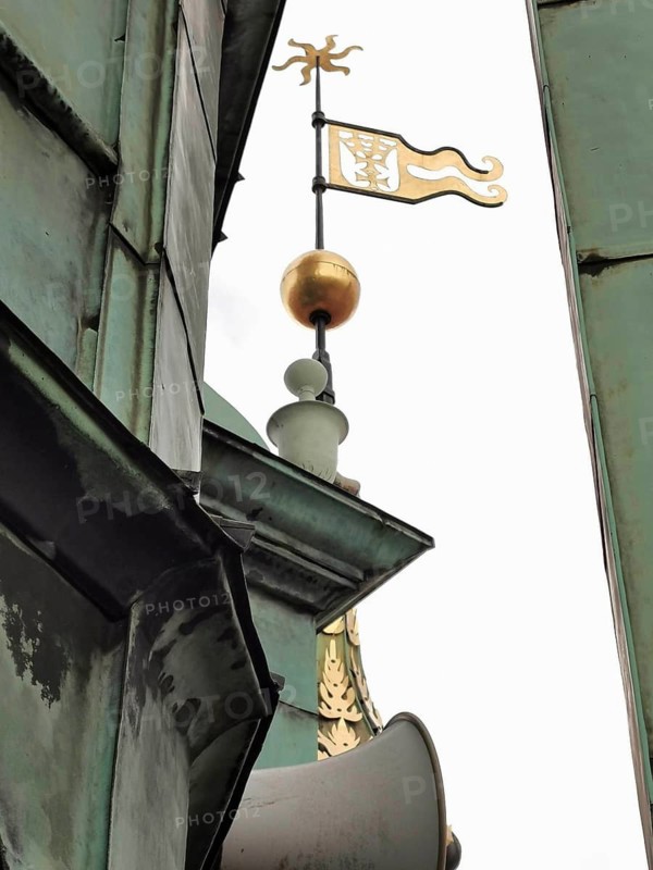 Close-up of an old tower with weather vane and golden ball on oxidized metal, old town of Danzig, Poland
