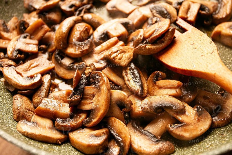 Fried mushrooms in a frying pan, with a wooden fork, homemade, no people
