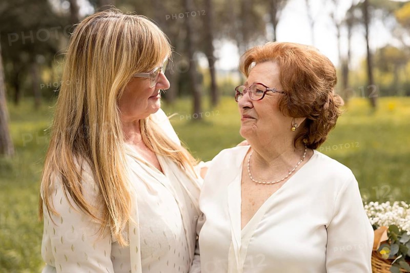 A touching moment captured between a mother and daughter sharing a warm embrace outdoors, symbolizing family love and connection. They stand together surrounded by nature's beauty