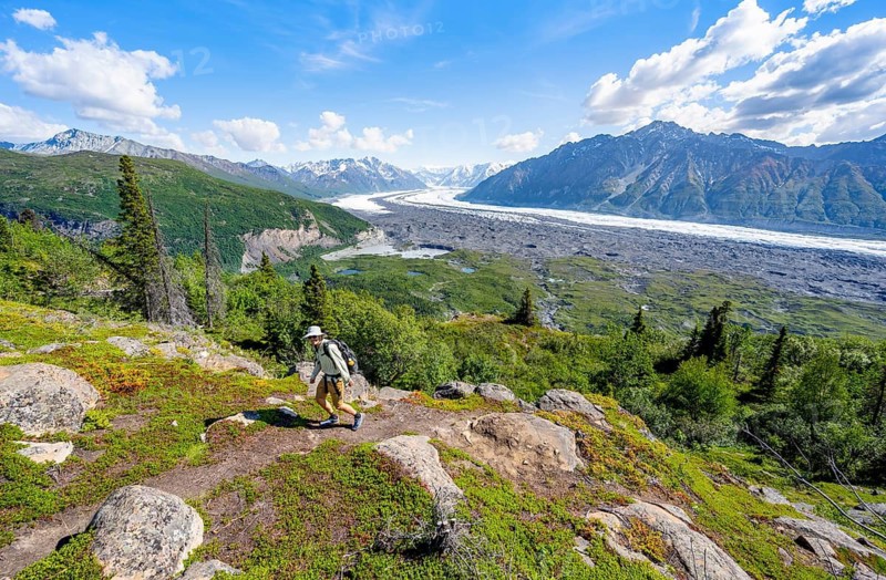 Young man on a hiking trail, view of impressive mountain landscape with Matanuska glacier and glaciated mountain peaks, Lion's Head, Chugach Mountains, Alaska, USA