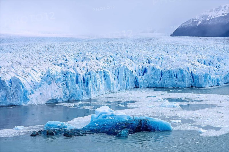 Perito Moreno glacier with glowing blue ice front, Lake Argentino surrounded by snow-capped mountains under cloudy sky, Los Glaciares National Park, Santa Cruz Province, Patagonia, Argentina