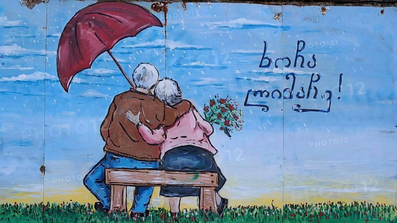 Mural of an elderly couple sitting on a bench with an umbrella, Georgia