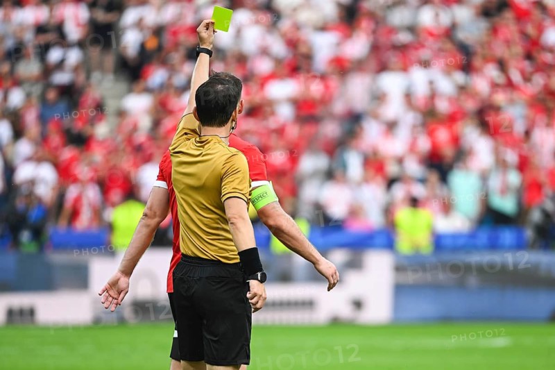 Referee shows yellow card during soccer match at the stadium