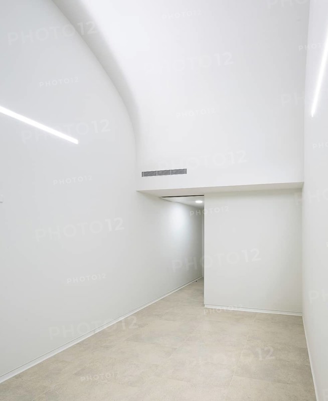 Minimalistic hallway of hospital featuring sleek white walls, soft ambient lighting, and a curved ceiling. The space exudes elegance and simplicity with clean architectural lines