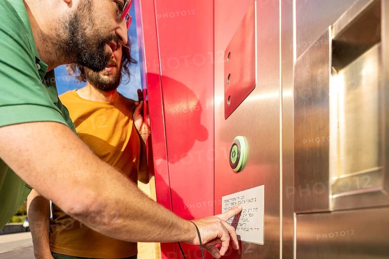 A blind man is guided by his friend at a tactile kiosk They communicate using a Braille panel, showcasing teamwork and accessibility in technology