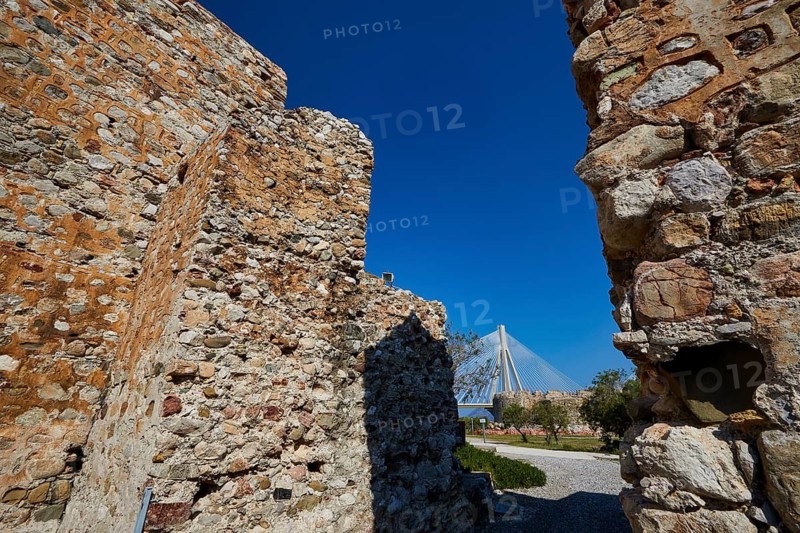 Stone walls of a ruin with a view of a modern bridge under a clear sky, Rio-Antirrio cable car bridge, Rio fortress, Patras, Peloponnese, Greece