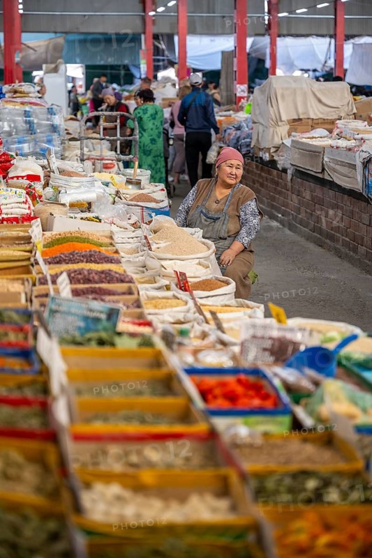 Traditional woman selling spices, flour and food, market stall at Osh Bazaar, Bishkek, Kyrgyzstan