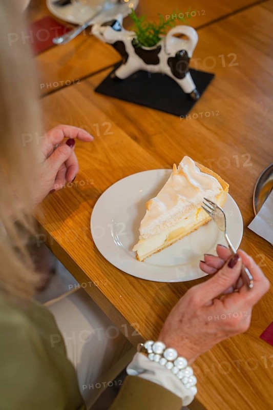 Woman enjoying a piece of lemon cake with meringue in a café, autumn creations, Cafe Kuh, Deckenpfronn, Black Forest, Germany