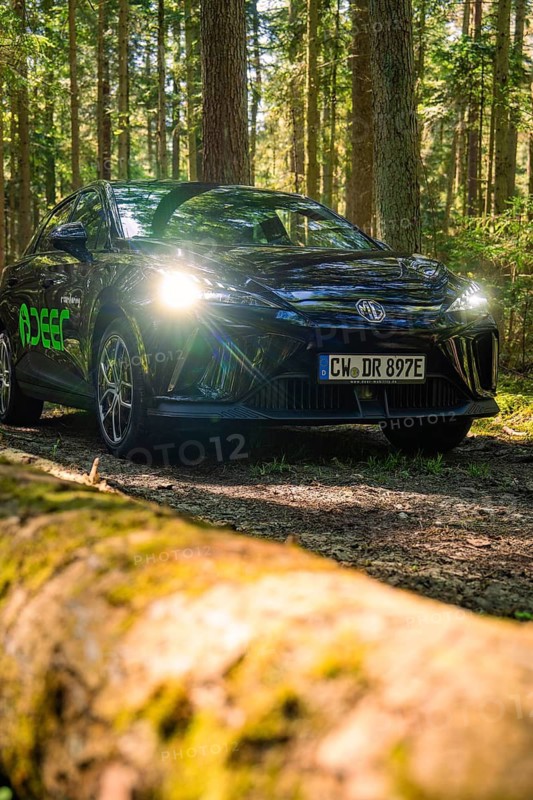 Black car with shining headlights on a forest path, Deer E- Carsharing, Calw, Black Forest, Germany