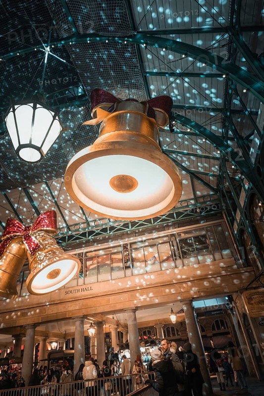 Large Christmas bells and lights project patterns onto the walls in a festive shopping mall, AppleMarket, London, United Kingdom