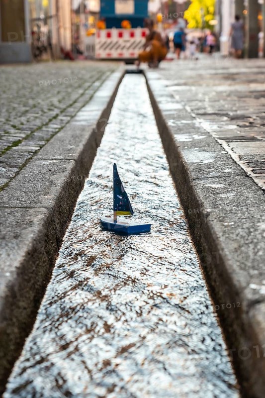 Toy boat sailing on the water canal in Freiburg im Breisgau, Germany