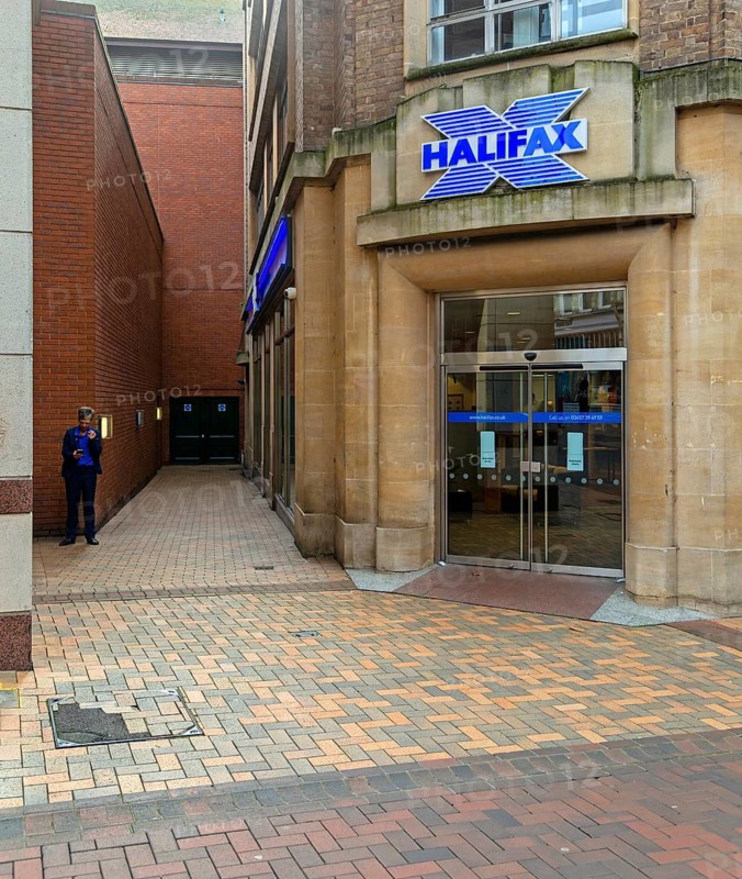 Woman having a cigarette break in alleyway next to Halifax bank, Ipswich, Suffolk, England, UK