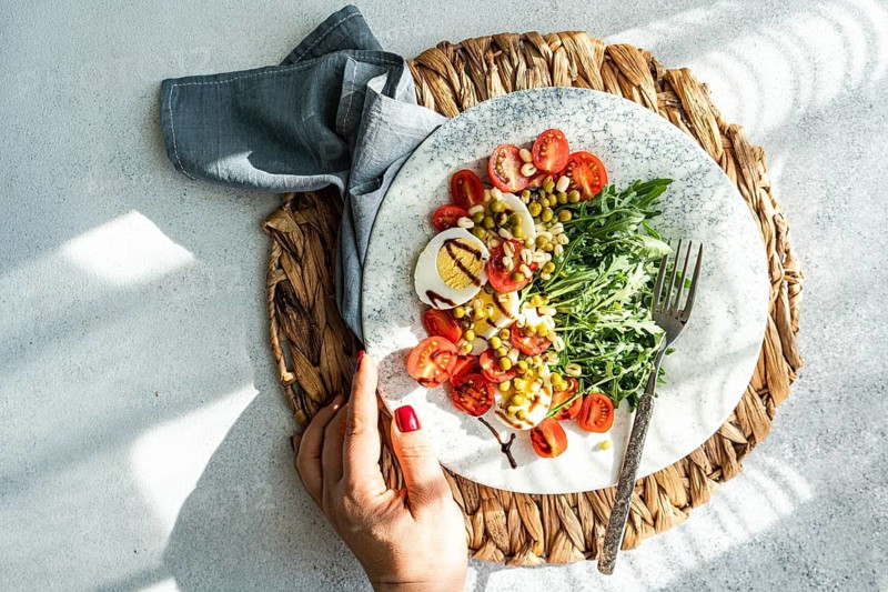 A nutritious keto lunch featuring boiled eggs, fresh rocket, cherry tomatoes, canned green peas, and sprouted green beans drizzled with balsamic sauce. Perfect for a healthy diet