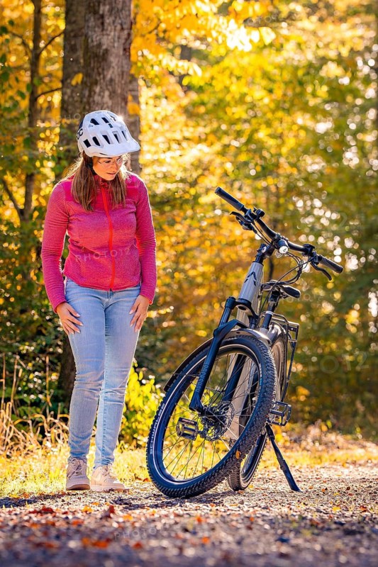 Woman looking at ebike in autumn forest, Black Forest, Gechingen, Germany