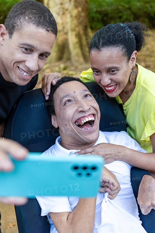 Two siblings share a heartfelt moment, taking a selfie with their disabled brother with cerebral palsy, showcasing love, connection, and happiness in an outdoor setting