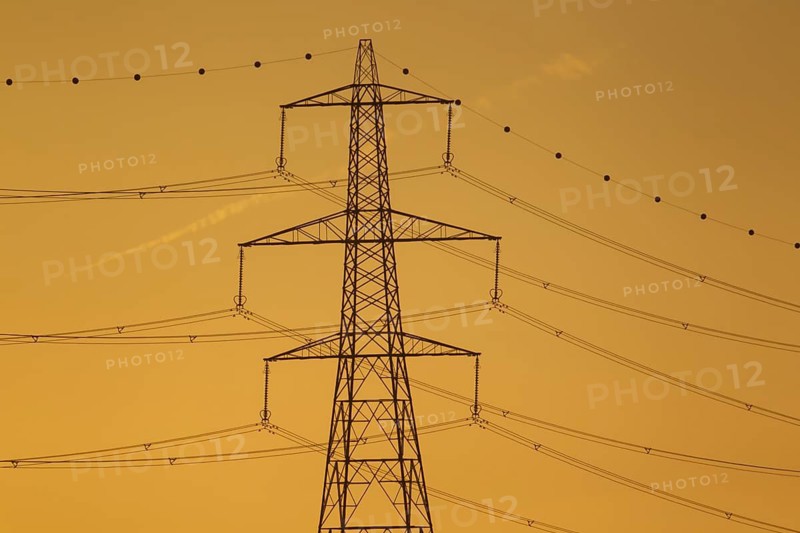 Electricity power pylon and cables silhouette at sunset, Lincolnshire, England, United Kingdom