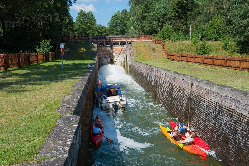 Boats and canoes in a lock, surrounded by old brick walls and summer landscape, Sluza Paniewo, lock between the lakes Paniewo and Krzywe, Plaska, Powiat Augustowski, Podlaskie Voivodeship, Poland