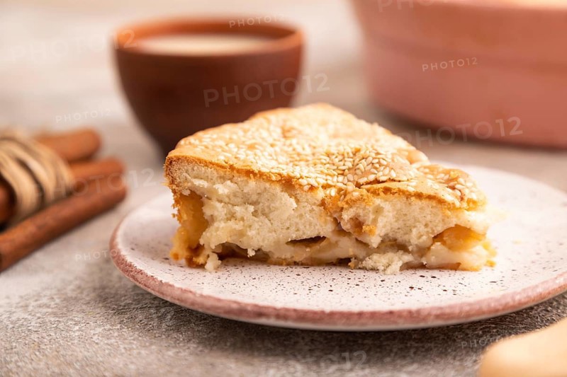 Apple Charlotte cake on brown concrete background and orange linen textile, cup of milk, side view, close up, selective focus