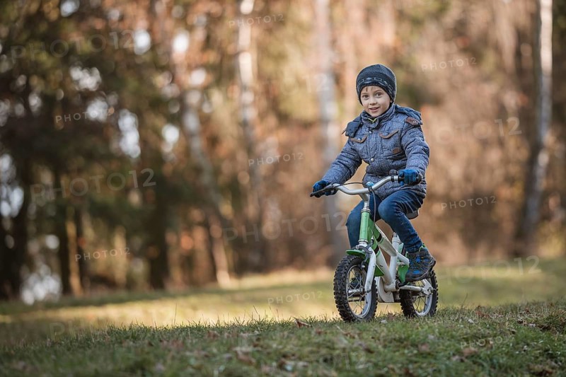 Six years old boy rides bicycle from the hill in the park