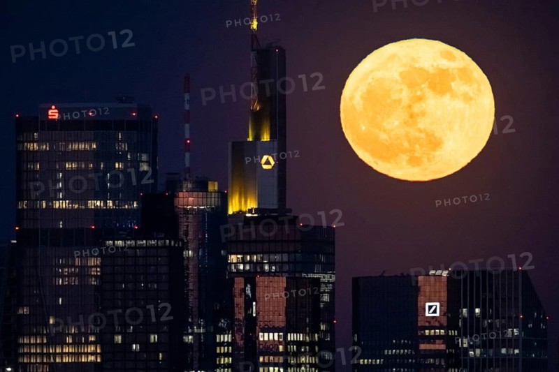 The full moon passes behind the Frankfurt banking skyline, Frankfurt am Main, Hesse, Germany