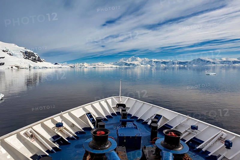 Ship on calm water in arctic landscape with snowy mountains and clouds, The landscape in the Southern Ocean in Antarctica