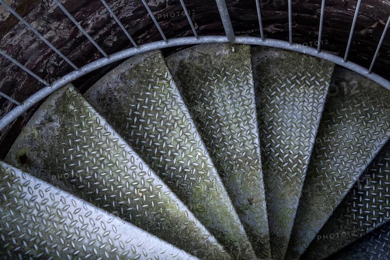Steps of old metal spiral staircase disappear in darkness