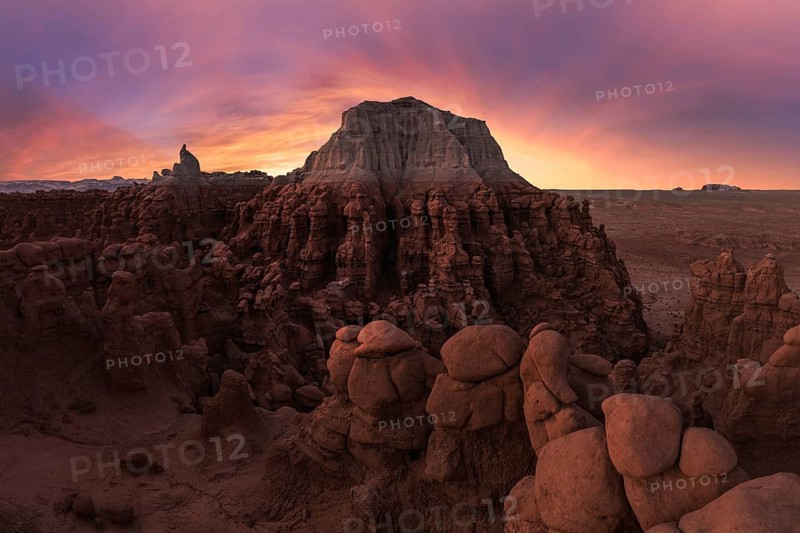 Mesmerizing sunset over sandstone formations in Goblin Valley State Park, Utah. The vibrant hues illuminate the unique rock structures, creating a magical desert scene