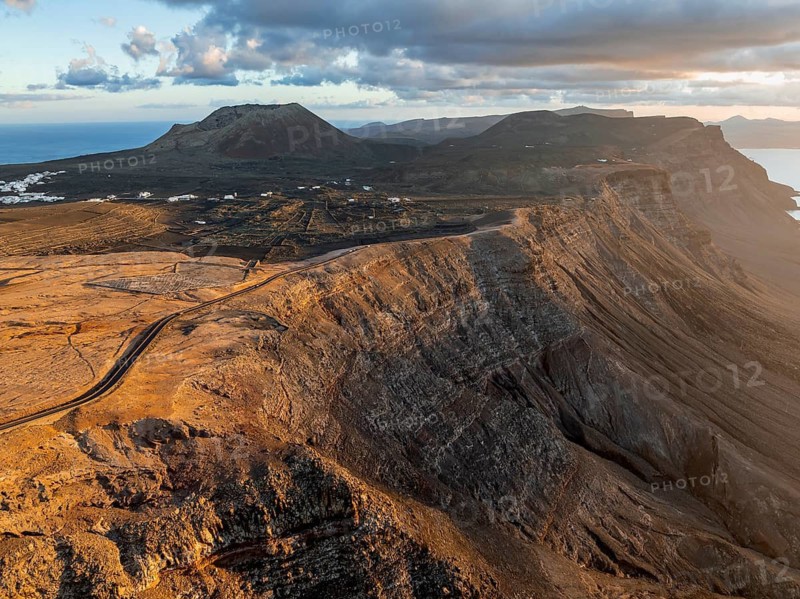 Volcán de la Corona and cliffs in evening light, steep cliffs on the coast near Mirador del Porrito, aerial view, at sunset, Lanzarote, Canary Islands, Spain