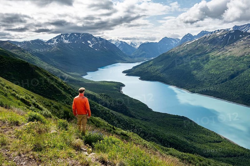 Mountaineer enjoys views of blue lake and mountains on Twin Peaks Trail, Eklutna Lake, Chugach Mountains, Chugach State Park, Alaska, USA