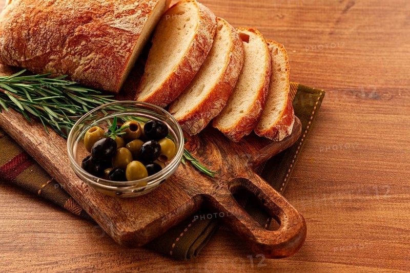 Sliced ciabatta, on a chopping board, with rosemary and olives, Italian bread, close-up, Italian cuisine, breakfast, no people