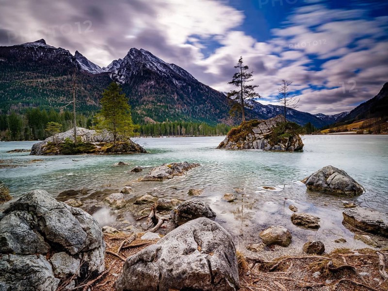 Rocks in frozen Hintersee, high cold and blurred clouds above, long exposure, Berchtesgaden National Park, Ramsau, Upper Bavaria, Bavaria, Germany