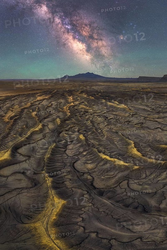 Stunning view of the Milky Way illuminating the sandstone ridges of a desert in Utah, USA. The celestial display complements the rugged, intricate terrain below
