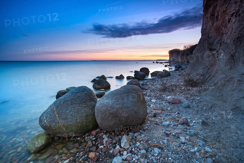 Rocky beach with large boulders on the cliffs on the Bay of Greifswald at dusk after sunset, Mönchgut nature reserve, Groß Zicker, Mönchgut peninsula, Rügen island, Mecklenburg-Western Pomerania, Germany