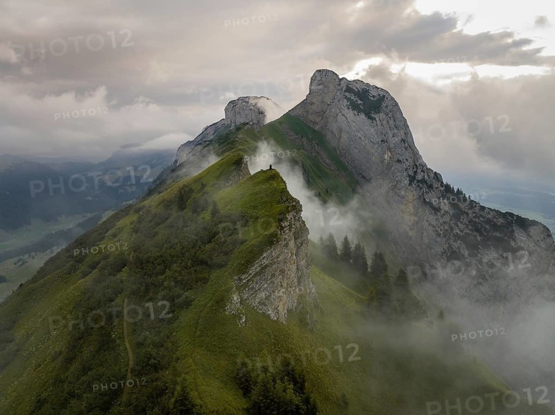 A breathtaking view of Saxer Lucke in Switzerland, showcasing rugged mountain peaks surrounded by mist and lush greenery. The serene atmosphere captures the essence of Alpine beauty