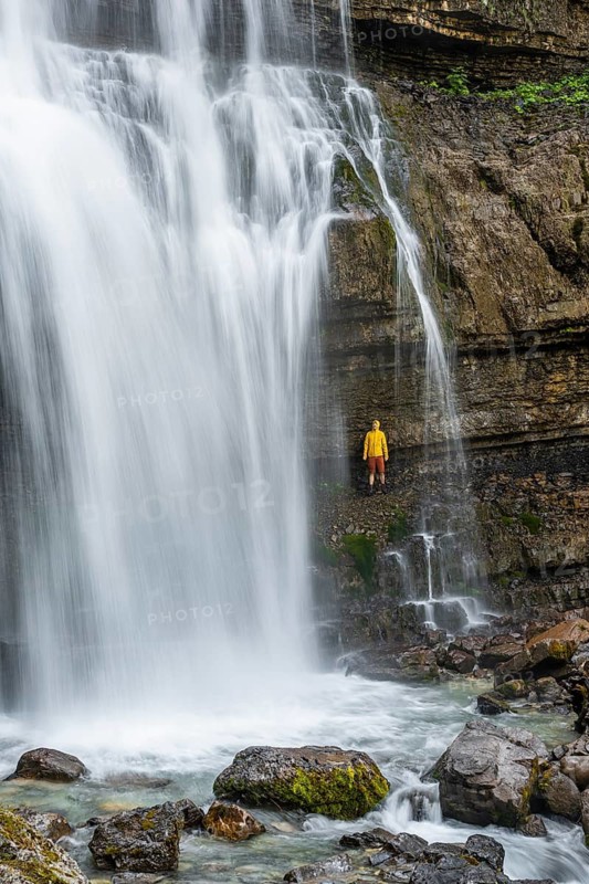 Adventure, Little hiker under large Cascata di Mezzo waterfall, long exposure, Vallesinella, Brenta, Trentino, Italy