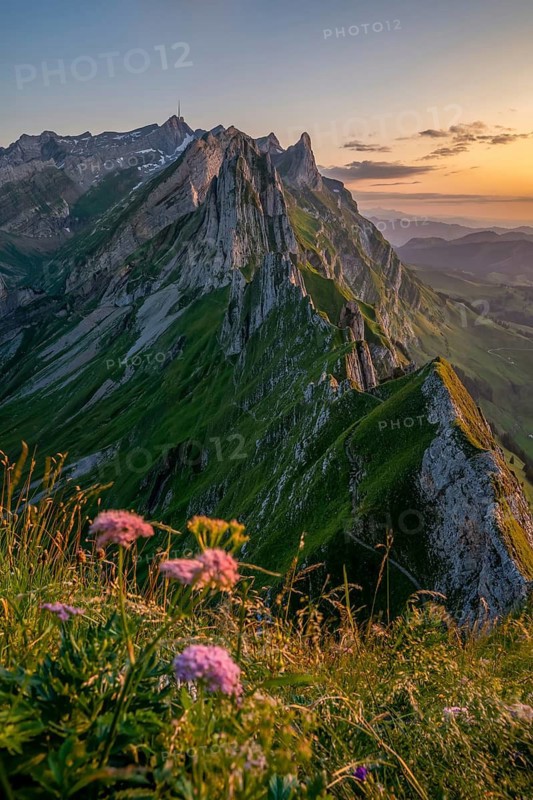 A breathtaking view of Altenalp Turm in Switzerland during sunset, showcasing rugged peaks and vibrant alpine meadows under a golden sky, creating a perfect natural retreat