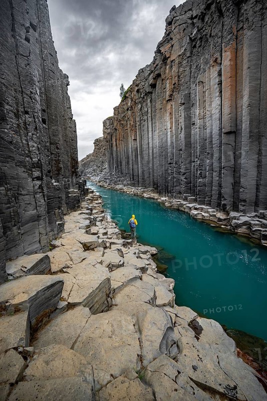 Tourist standing by the river in Stuðlagil Canyon, turquoise blue river between basalt columns, Egilsstadir, Iceland