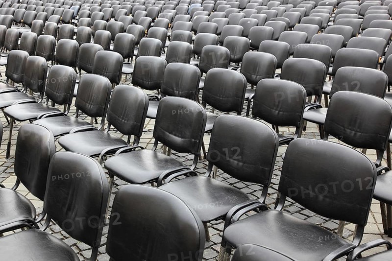 Chairs covered with gray plastic stand in rows in a function room, empty, vacant, seating