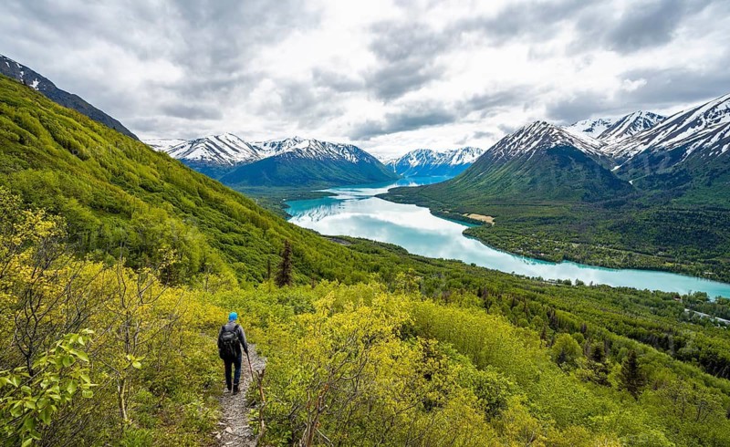 Climbers on a hiking trail, Slaughter Ridge Trail, view of snowy mountains in spring and turquoise blue Kenai Lake Lake, Cooper Landing, Kenai Peninsula, Alaska, USA
