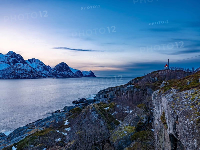 Small lighthouse at the end of Husøy island with a view across the fjord to the sea, Senja island, Troms, Norway