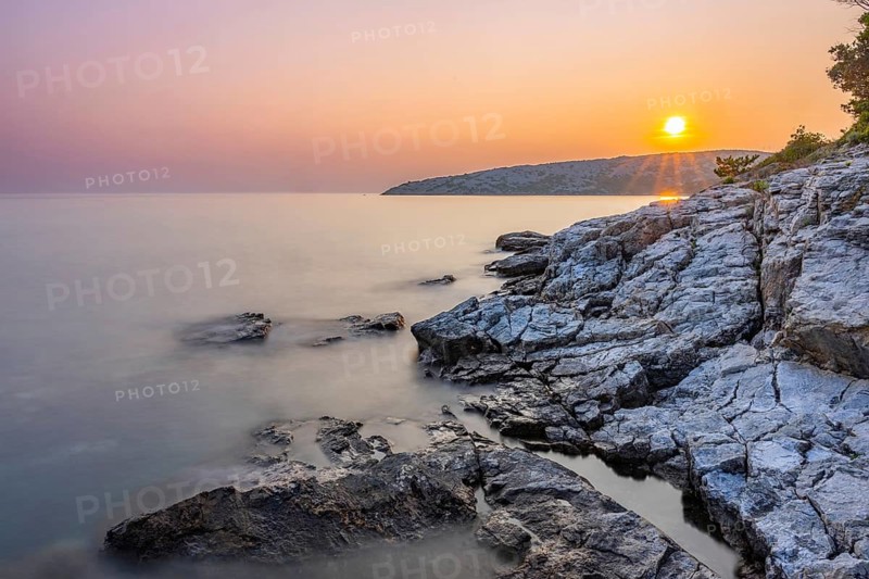 Sunset over crystal clear water on the beach of Ustrine Bay on the island of Cres, long exposure, Croatia