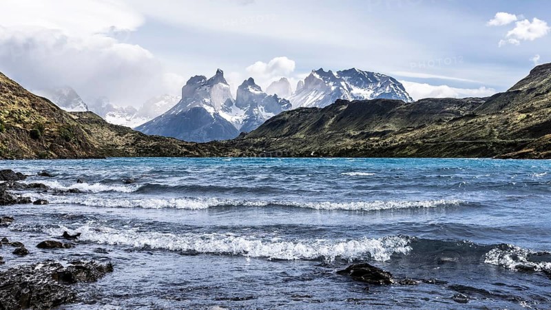 Cuernos del Paine, snow-capped mountain range behind wind-moving Lake Pehoé with turquoise water, Torres del Paine National Park, Magallanes Region, Chile