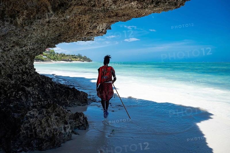 A Masai man walks along a beautiful Indian Ocean beach
