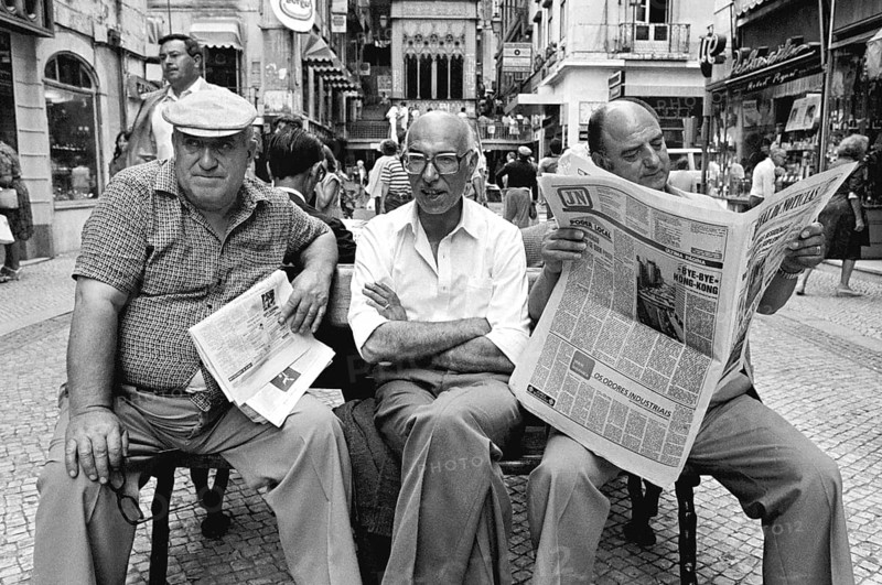 Three men sitting on a bench in the historic city center of Lisbon, Lisbon, Portugal