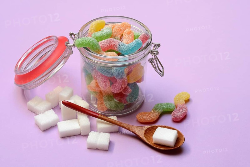 Lots of colorful jelly sweets in glass containers and sugar cubes, sugar consumption