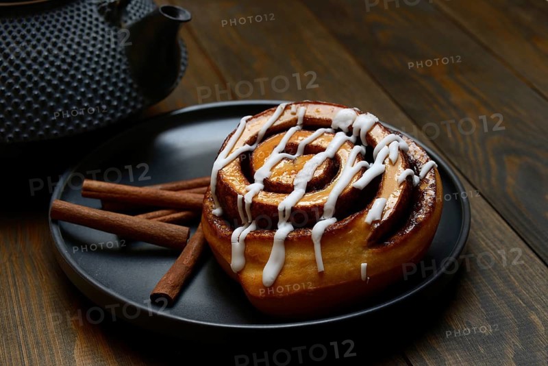 Cinnamon roll on plate and cinnamon sticks