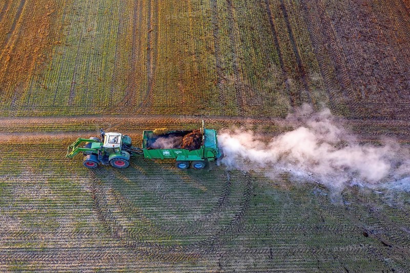 Tractor with manure spreader, agricultural machine used to distribute manure over a field as fertilizer in spring