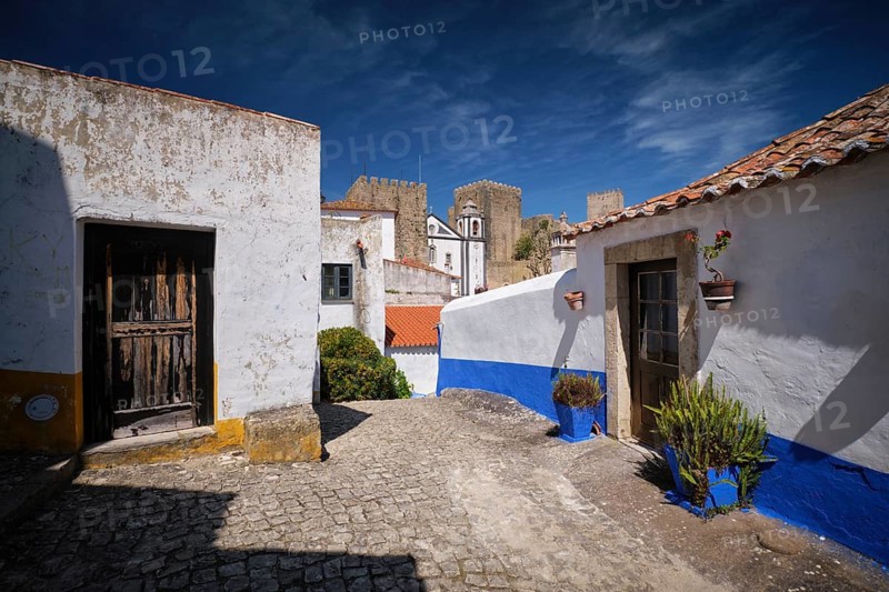 Narrow streets of Obidos, Portugal, white houses and castle walls under a bright sky