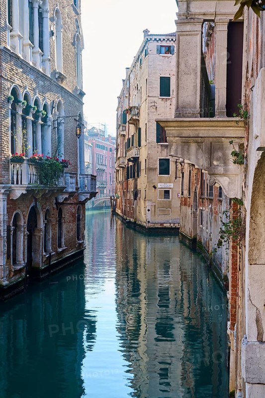 View from a gondola on a waterway in Venice going through the houses on a quiet and sunny morning in winter, Italy